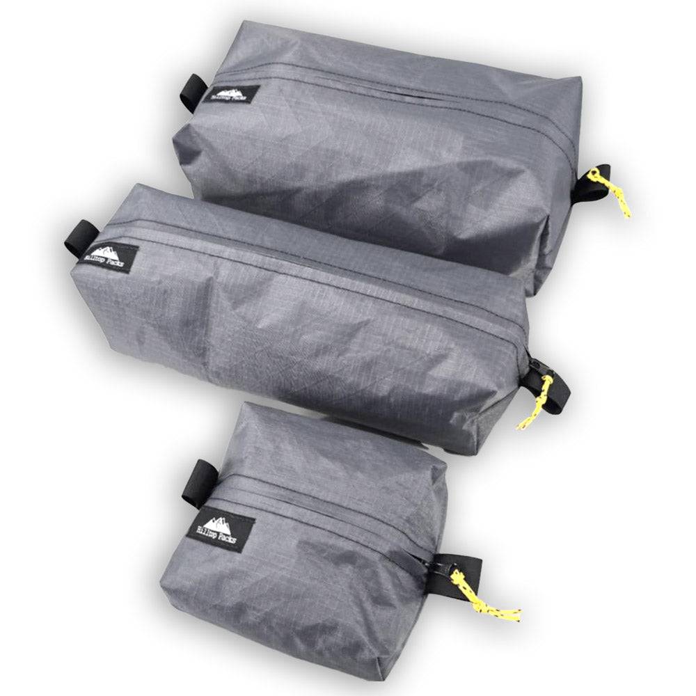 Three gray compression bags with black straps and yellow tags on a white background