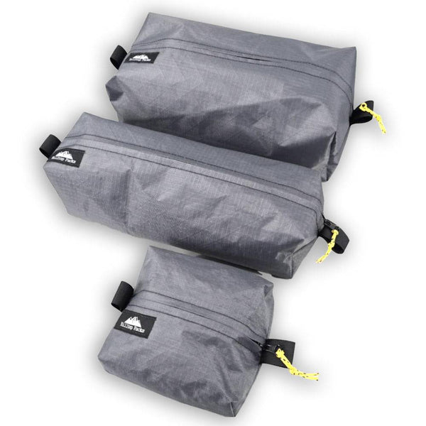 Three gray compression bags with black straps and yellow tags on a white background